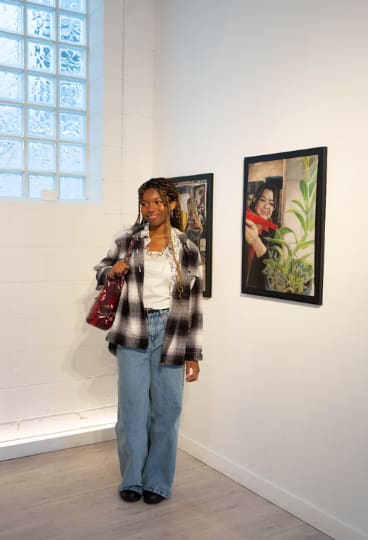 A young artist standing beside her work at a curated Antaraloka exhibition